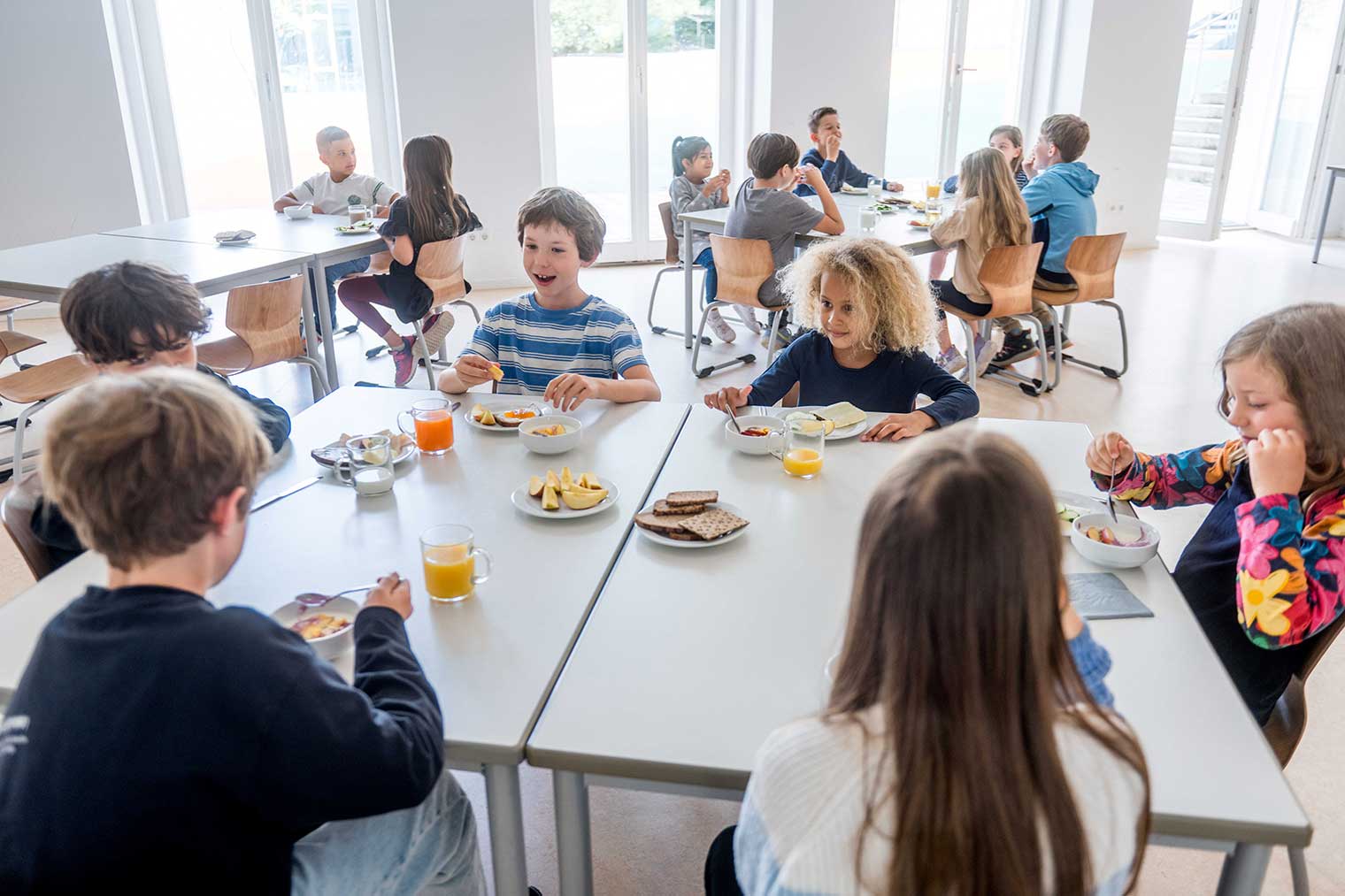 Kinder essen am Tisch in der Schulkantine